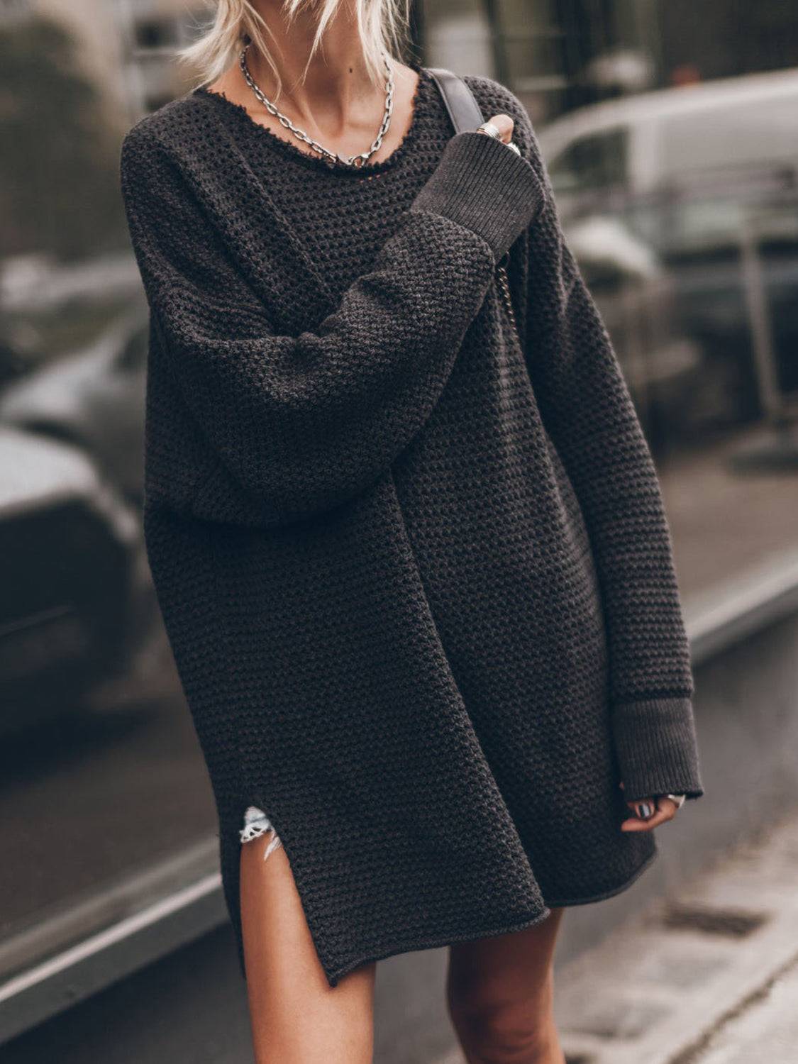 a woman walking down the street wearing a black sweater and ripped shorts