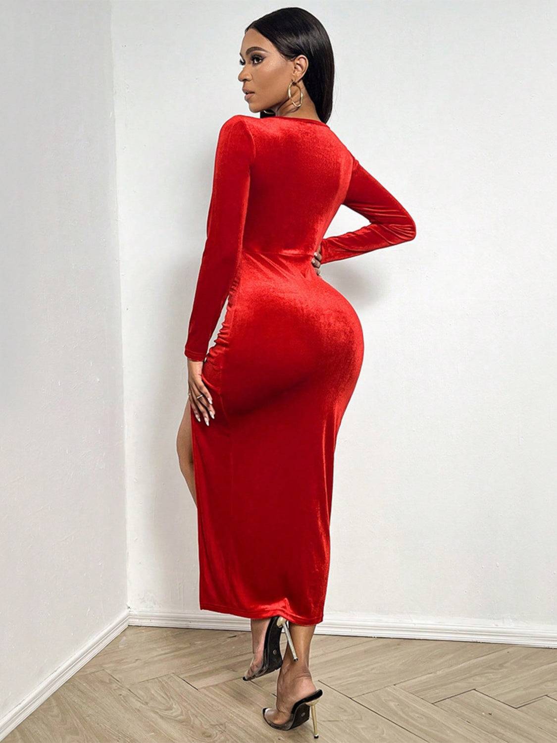 a woman in a red dress is leaning against a wall